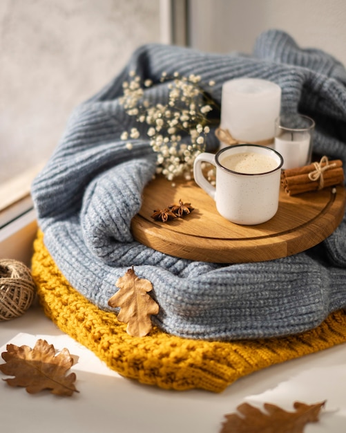 High angle of cup of coffee with sweater and leaves