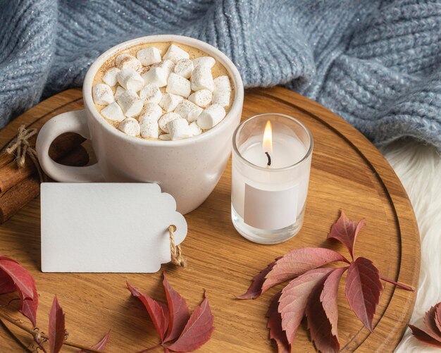 High angle of cup of hot cocoa with marshmallows and candle