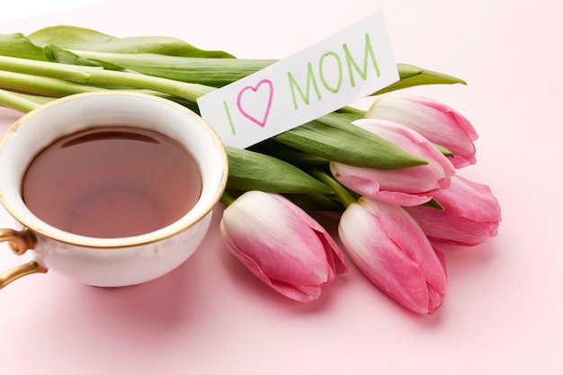 Foto gratuita tazza dell'angolo alto con tè accanto ai tulipani