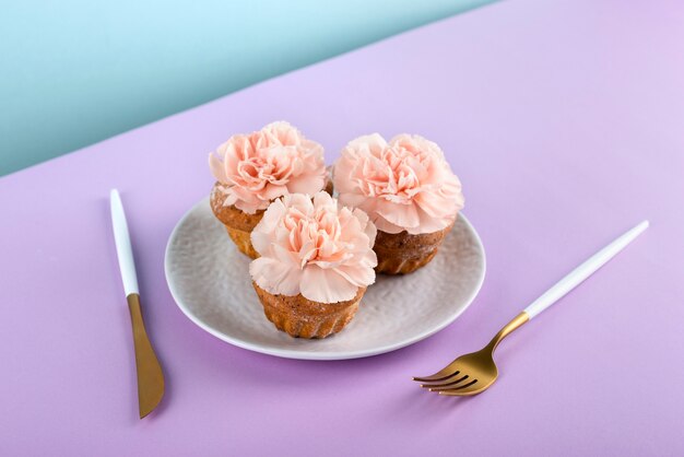 보라색 배경에 꽃과 높은 각도 컵 케이크