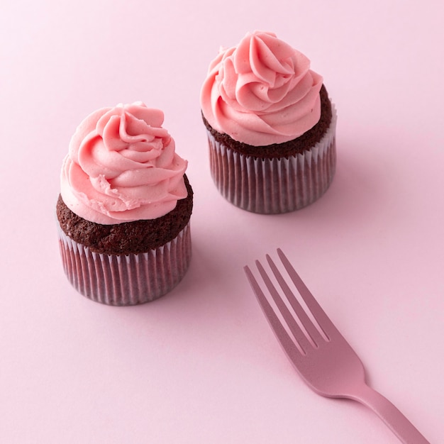 핑크 아이싱과 포크가있는 하이 앵글 컵 케이크