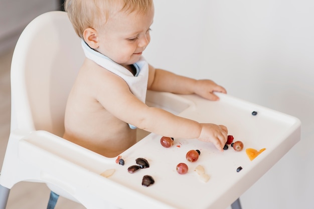 Foto gratuita bambino sveglio di alto angolo che mangia da solo