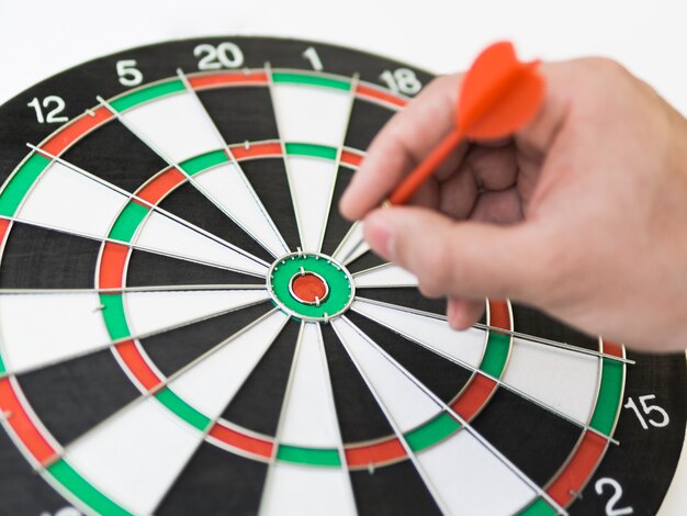 High angle of dart board with hand putting a dart in