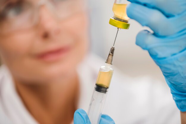 High angle of defocused female scientist using a syringe