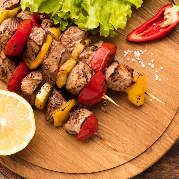 High angle of delicious kebab on chopping board with lemon and salad