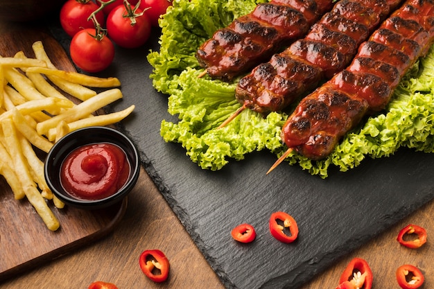 High angle of delicious kebab on slate with tomatoes and fries