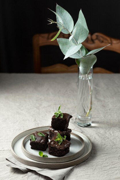 Высокий угол десерта на тарелке с растением и вазой