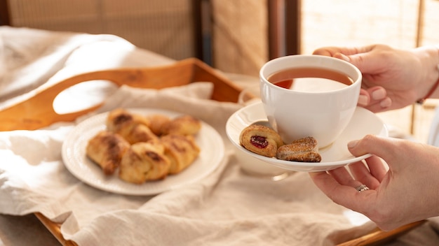 High angle of desserts on tray with person holding tea cup