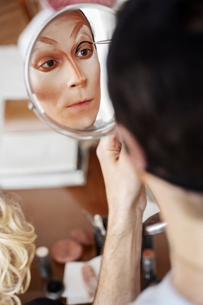 Трансвестит под большим углом держит зеркало