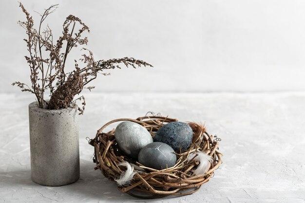 Alto angolo di uova di Pasqua nel nido di uccelli con vaso di fiori