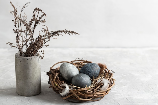 High angle of easter eggs in bird nest with vase of flowers