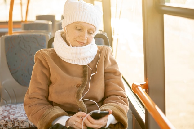 Высокий угол старшая женщина в автобусе прослушивания музыки