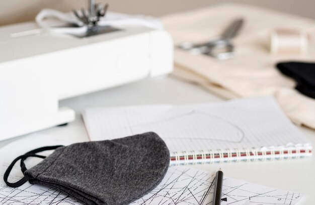 High angle of face mask with sewing machine and notebook