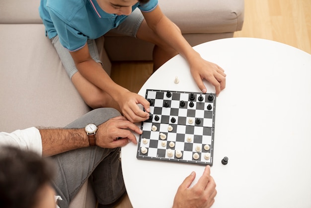 High angle father and child playing chess