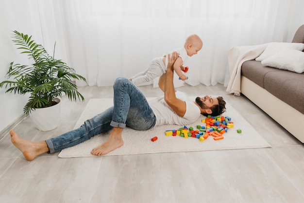 Foto gratuita alto angolo del padre che gioca sul pavimento con il bambino