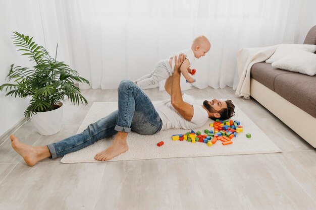 赤ちゃんと一緒に床で遊ぶ父親の高角度