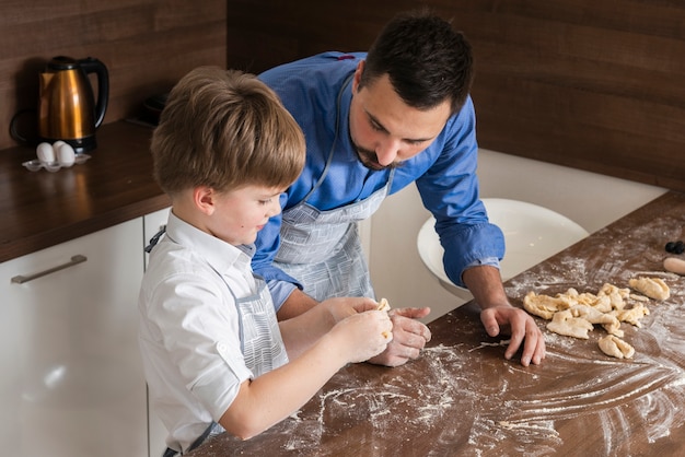 High angle father and son making shapes of dough