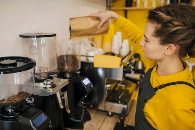 Foto gratuita alto angolo del barista femminile che macina caffè