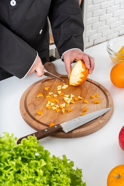 High angle of female chef cutting orange