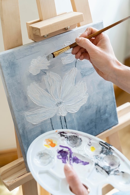 High angle of female hands painting a flower at home