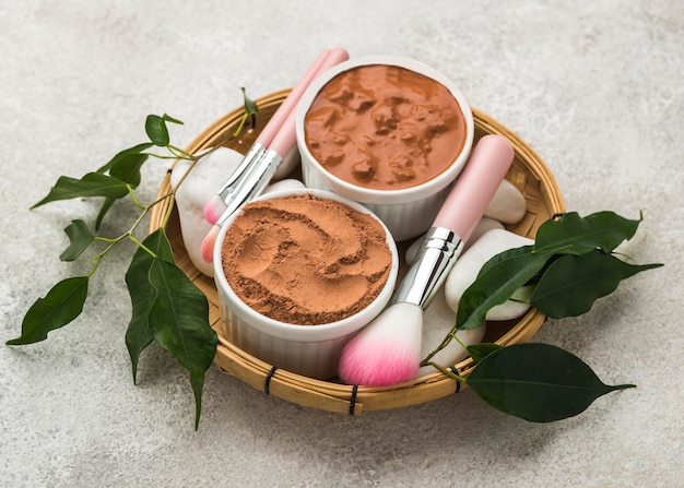 Free photo high angle of fine powder in bowls with brushes and leaves