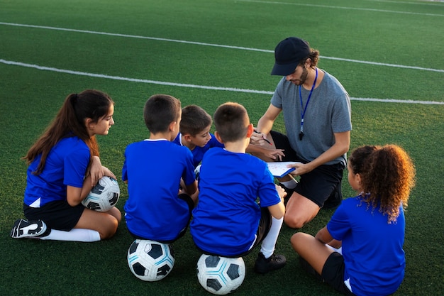 Foto gratuita allenatore di calcio ad alto angolo che insegna ai bambini