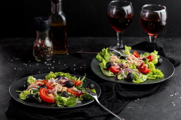 High angle fresh meal with dark tableware and wine glasses