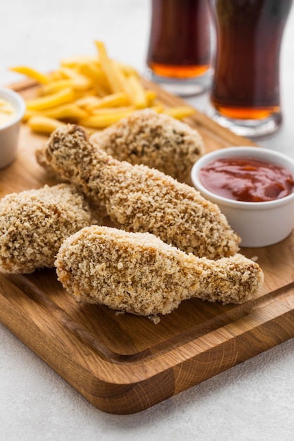 Alto angolo di cosce di pollo fritte con salsa e bevande gassate