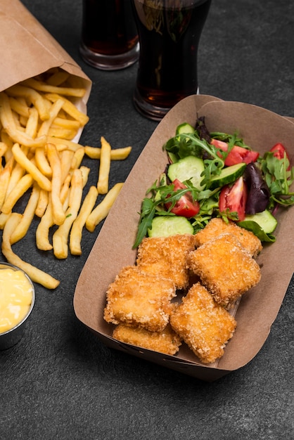 High angle of fried chicken nuggets with french fries and salad