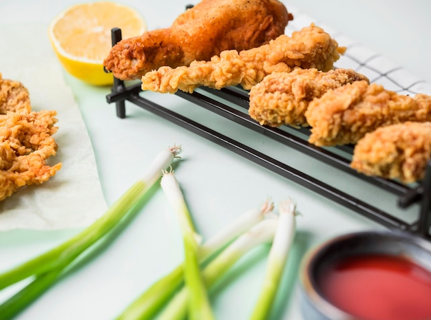 High angle fried chicken on tray with sauce, green onions and lemon