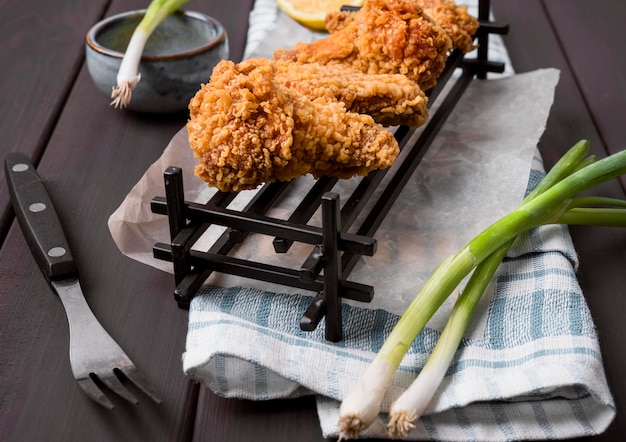 High angle fried chicken wings on tray with green onions and fork