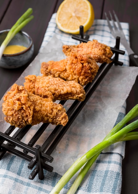 Free photo high angle fried chicken wings on tray with green onions and lemon