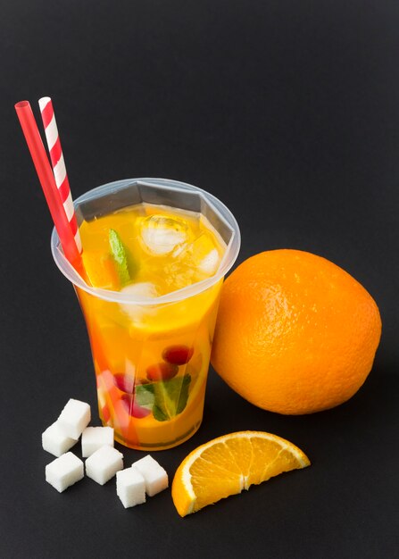 High angle of fruit juice in cup with straws