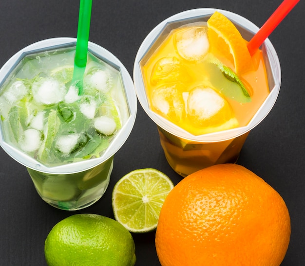 Free photo high angle of fruit juice in cups with straws