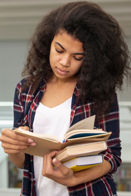 High angle girl carrying stack of books while reading