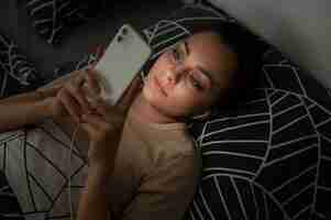 무료 사진 스마트폰으로 침대에 누워 하이 앵글 소녀