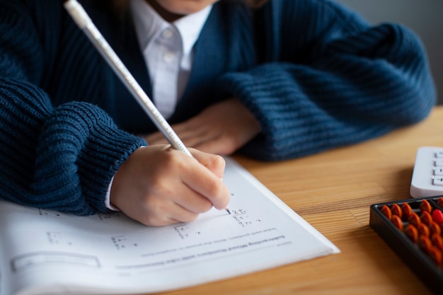 Foto gratuita ragazza dell'angolo alto che impara la matematica a scuola