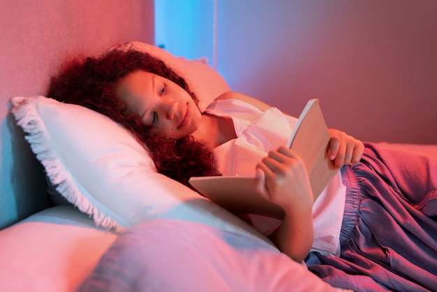 Free photo high angle girl reading in bed