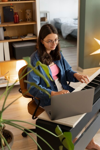 Девушка под высоким углом с ноутбуком и фортепиано