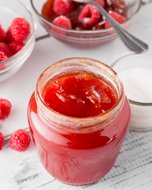 High angle of glass jar with raspberry jam and fruits