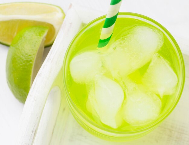 High angle of glass of soft drink with lime and straw