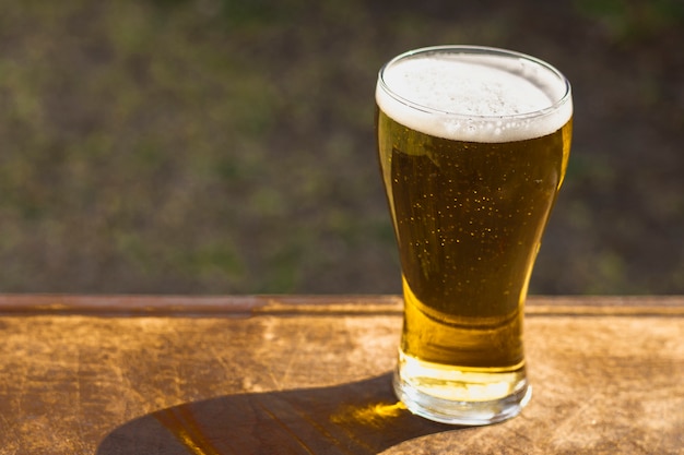 High angle glass with foaming beer on table