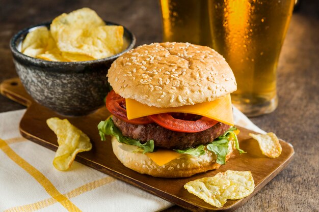 High angle of glasses of beer with cheeseburger and potato chips