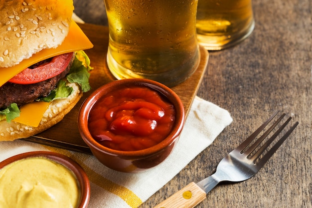 High angle of glasses of beer with cheeseburger and sauce