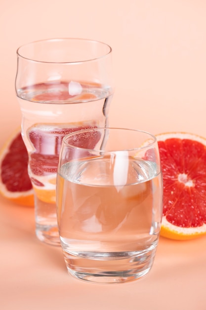 High angle glasses of water with red oranges
