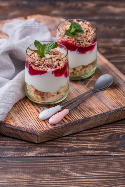 High angle of glasses with yogurt and cereal on wooden board