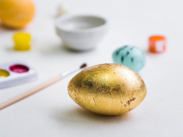 Высокий угол золотого пасхального яйца с расфокусированным палитрой и кистью