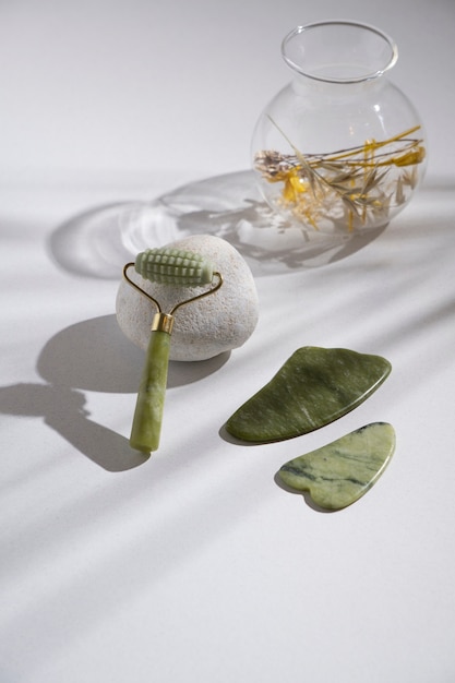 Free photo high angle green face roller and gua sha