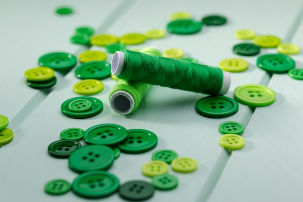 High angle of green thread reels and buttons