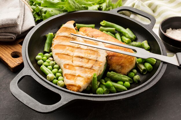 High angle grilled chicken and peas in pan